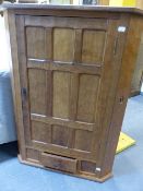 ALAN GRAINGER. ACORNMAN. A WALL HANGING CORNER CABINET WITH MULTI PANEL SINGLE DOOR OVER A SMALL