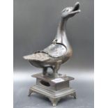 A CHINESE BRONZE DUCK CENSER STANDING ON A PLINTH WITH FOUR BRACKET LEGS, IT'S OPEN BEAK TURNED TO