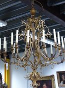 A LARGE GILDED WROUGHT IRON EIGHTEEN LIGHT CHANDELIER IN THE BAROQUE TASTE WITH SCROLL WORK