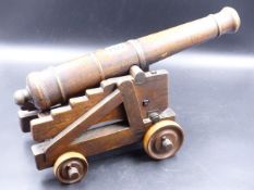 AN ANTIQUE HANDMADE MAHOGANY MODEL OF A CANNON ON A STEPPED WHEELED CARRIAGE WITH ELEVATION