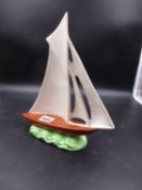 A 1930'S SHORTER POTTERY YACHT, THE FIVE WHITE SAILS RAISED ABOVE AN OCHRE HULL AND GREEN WAVES. H.