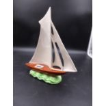 A 1930'S SHORTER POTTERY YACHT, THE FIVE WHITE SAILS RAISED ABOVE AN OCHRE HULL AND GREEN WAVES. H.