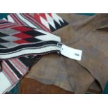 AN AMERICAN INDIAN PIECED LEATHER TRIBAL BLANKET WITH BRAIDED FRINGE AND A NAVAJO MAT WITH GEOMETRIC