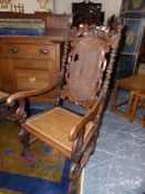 AN ANTIQUE CAROLEAN STYLE CARVED WALNUT ARMCHAIR WITH CANE BACK AND SEAT.