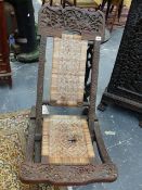 A BURMESE CARVED HARDWOOD FOLDING CHAIR WITH CANE SEAT AND BACK TOGETHER WITH A SMILIAR HARDWOOD