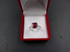 A RUBY AND DIAMOND RING, STAMPED 750 AND TESTED AS WHITE GOLD. THE CENTRAL RUBY IS SUSPENDED IN A