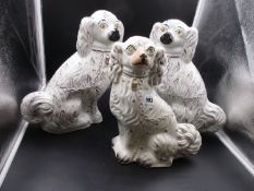 A PAIR OF STAFFORDSHIRE POTTERY SEATED SPANIELS DETAILED IN PINK LUSTRE. H.35cms AND ANOTHER