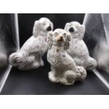 A PAIR OF STAFFORDSHIRE POTTERY SEATED SPANIELS DETAILED IN PINK LUSTRE. H.35cms AND ANOTHER