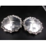 A NEAR PAIR OF GEORGIAN SILVER SALVERS WITH A SCROLLING SHELL PATTERN RIM, A CREST ENGRAVED CENTRE