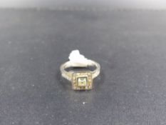 A 14K STAMPED DIAMOND RING,TESTED AS 14ct WHITE GOLD. THE CENTRAL DIAMOND IS A PRINCESS CUT IN A RUB