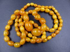 A ROW OF AMBER BEADS. A GRADUATED ROW OF CYLINDRICAL AMBER BEADS, LENGTH 58cms, GRADUATING IN SIZE