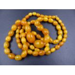 A ROW OF AMBER BEADS. A GRADUATED ROW OF CYLINDRICAL AMBER BEADS, LENGTH 58cms, GRADUATING IN SIZE