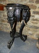 A VICTORIAN CARVED AND EBONISED STAND WITH ELEPHANT FORM SCROLLING SUPPORTS. H.72cms.