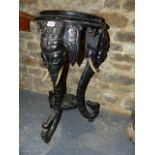 A VICTORIAN CARVED AND EBONISED STAND WITH ELEPHANT FORM SCROLLING SUPPORTS. H.72cms.