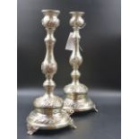 A PAIR OF CONTINENTAL SILVER METAL EMBOSSED DECORATED CANDLESTICKS WITH LOADED BASES. H.37cms. (