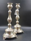 A PAIR OF CONTINENTAL SILVER METAL EMBOSSED DECORATED CANDLESTICKS WITH LOADED BASES. H.37cms. (