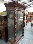 A FLEMISH HIGHLY CARVED OAK GLAZED FLOOR STANDING DISPLAY CABINET WITH FLANKING FIGURAL PILASTERS