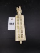 A CHINESE IVORY CRIBBAGE BOARD WITH CARVED FIGURAL HANDLE AND PEG HOLDER IN BASE.