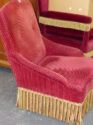 AN ANTIQUE CONTINENTAL BUTTON BACK SALON ARMCHAIR WITH RIBBED ROSE UPHOLSTERY AND BRAID AND FRINGE.