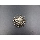 AN ANTIQUE OLD CUT DIAMOND STARBURST BROOCH SET IN SILVER OVER GOLD AND TESTED. THE CENTRAL