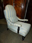 A VICTORIAN DEEP SEAT LOW ARMCHAIR ON TURNED FORELEGS WITH LATER PALE BLUE STRIPE UPHOLSTERY.