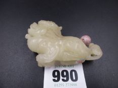 A CHINESE PALE OLIVE GREEN HARDSTONE SNUFF BOTTLE AND STOPPER CARVED AS A RECLINING QILIN. W.7cms.