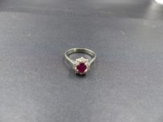 A RUBY AND DIAMOND CLUSTER RING, STAMPED 750, TESTED AS 18ct WHITE GOLD. THE CENTRAL OVAL RUBY IS