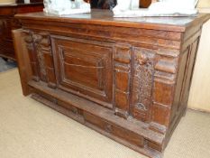 AN 18th.C.CONTINENTAL CARVED OAK SIDE CABINET WITH SINGLE PANEL DOOR FLANKED BY CHERUBIC AND FOLIATE