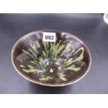 A CHINESE TRUNCATED CONICAL BOWL, THE TREACLE BLACK GLAZED SPLASHED AND STREAKED IN GREEN. Dia.14.