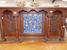 A PERSIAN GLAZED FIGURAL RELIEF PLAQUE MOUNTED IN A CARVED OAK SURROUND WITH COLUMN SUPPORTS. W.