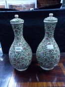 A PAIR OF MIDDLE EASTERN POTTERY BOTTLE FORM VASES WITH LIDS AND FLOWERHEAD AND FOLIATE