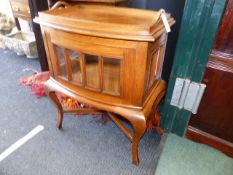 A COLONIAL HARDWOOD GLAZED CABINET OF BOWED FORM WITH INSET TRAY TOP AND BEVELLED GLASS PANES.