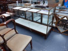 A GOOD VINTAGE MAHOGANY AND BRASS FRAMED GLASS SHOP COUNTER WITH FITTED SHELVES AND FOUR DOORS.