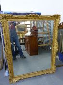 A LARGE WALL MIRROR WITH FOLIATE CARVED GILTWOOD FRAME AND BEVELLED PLATE. OVERALL 111 x 137cms.