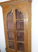 A 19th.C.PINE FLOOR STANDING CORNER CABINET WITH A PAIR OF ARCH TOP GLAZED DOORS ENCLOSING SHELVES