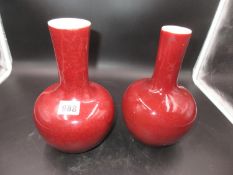 TWO CHINESE SANG DE BOEUF BOTTLE VASES, ONE WITH THE WIDER DIAMETER NECK WITH A MOTTLED RED GLAZE.