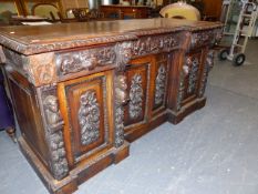 A VICTORIAN CARVED OAK INVERTED BREAKFRONT SIDEBOARD WITH THREE DRAWERS OVER FOUR PANEL DOORS ON