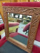 AN ARTS AND CRAFTS CARVED OAK MIRROR FRAME WITH TUDOR ROSE AND VINE DECORATION. 49 x 58cms.