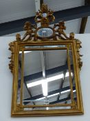 AN ANTIQUE STYLE GILT FRAMED SMALL WALL MIRROR WITH FOLIATE CREST, SIDE SWAGS AND MARGINAL PLATE. 87
