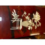 A JAPANESE RED LACQUER PLAQUE INLAID IN BONE AND STAGSHORN WITH A CRYSANTHEMUM BLOOM IN A BASKET