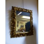 AN ANTIQUE CARVED GILTWOOD FLORENTINE FRAME MOUNTED AS A MIRROR WITH ELABORATE PIERCED SCROLL