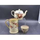 AN ANTIQUE CREAMWARE TEAPOT, TEA BOWL AND PINT MUG EACH PAINTED WITH COLOURED FLOWERS.