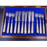 A MAHOGANY CASED SET OF TWELVE EASTERN FISH KNIVES AND FORKS WITH HEAVILY ENGRAVED AND CHASED
