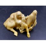 A JAPANESE IVORY GROUP OF A MONKEY WITH A FRUIT FROND ON THE BACK OF A RECLINING DEER. W.7.5CMS.