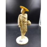 A JAPANESE SECTIONAL IVORY FIGURE OF A MAN STANDING WITH BASKET AT HIS HIP, HIS STRAW HAT SHADING