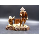 A JAPANESE WOOD AND IVORY GROUP OF A FATHER AND CHILD EITHER SIDE OF A TREE TRUNK AMONGST