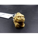 A JAPANESE MARINE IVORY NETSUKE CARVED AS ONE CHILD WEARING A LION MASK RAISING THE MASK HEAD OF A