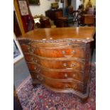 AN ANTIQUE CARVED MAHOGANY SERPENTINE FORM CHEST WITH BRUSHING SLIDE IN THE CHIPPENDALE TASTE, BLIND