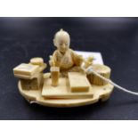 A JAPANESE IVORY GROUP OF A CRAFTSMAN SEATED AT HIS WORK, SIGNED. W.7CMS.