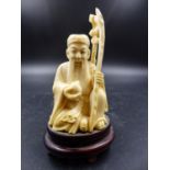 A JAPANESE IVORY FIGURE OF JUROJIN SEATED HOLDING A PEACH IN HIS RIGHT HAND AND A STAFF TIED WITH